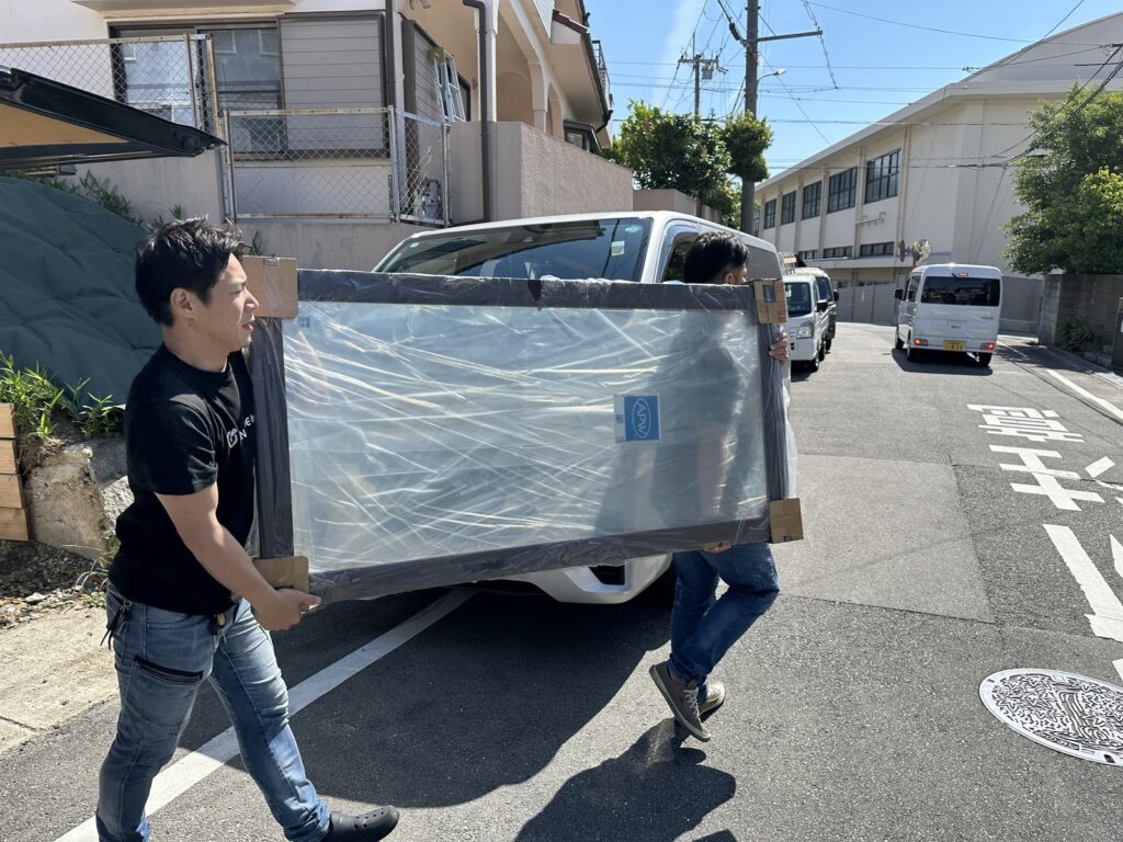 窓のカバー工法用の窓を2人がかりで運ぶマドアーズ！のスタッフ